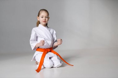 Greeting little girl in karate, position of the student on a white background.