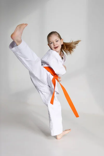 Little girl in kimono kicks, karate training.