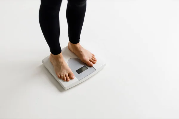 Weight loss and diet, women\'s legs on the scales on a white background.