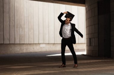 An upset and disappointed man in dark gateway, throws folder with resumes on floor, rage.