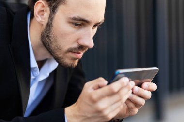 Modern young man playing on phone, browsing mobile news. Gadget Dependence.