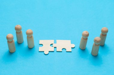 Wooden figures with pazzles on blue background. Agreement between business mans, cooperation and deal concept. Successful contract. 