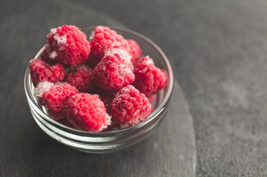 Siyah masada donmuş ahududu tabağı. Kış vitamini tatlısı.