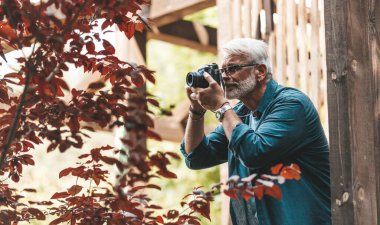 A mature man with a beard and a camera takes pictures, paparazzi. Retired active hobby, senior journalist.