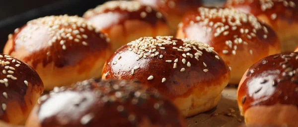 Fresh hot sweet buns with sesame seeds from the oven, homemade bakery.