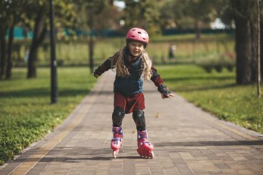Cute little girl in a helmet rollerblading, protection during sports and entertainment.