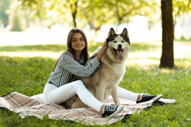 Evcil hayvanı olan bir kız parkta dinleniyor. Yumuşak, kabarık köpek.