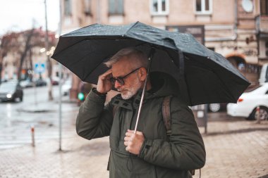 Migraine and headache when the weather changes. Unpleasant symptoms in a mature man in the rain.