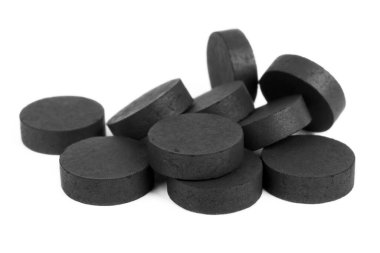 Tablets of black activated charcoal on a white background, help with poisoning and toxins.