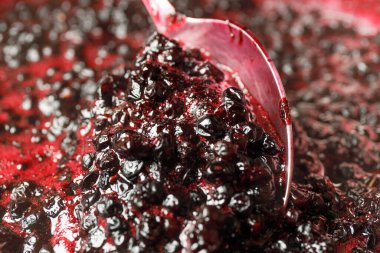 Preparation of homemade blueberry jam, spoon close-up.