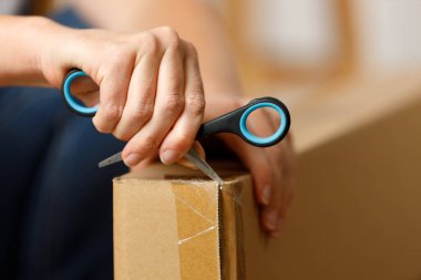Karton bir paketi makasla açıyorum, yakın plan. Online mağazadan mal teslimatı.
