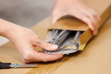 Yeni mobilyalarla dolu bir kutuyu açıyorum, yakın plan. Ev yenilenmesi.