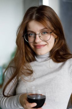 Bir bardak kırmızı şarapla çekici bir genç kadının portresi..