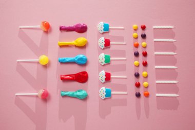 Çocuk doğum günü partisi, pembe arka plan (desen). Tatlı şekerler, parlak balonlar, şenlikli mumlar, kek ve pipetler..