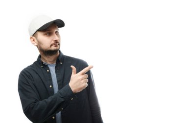 Fashionable white man with beard and cap shows finger on empty space for text. Look over there, pointing away.