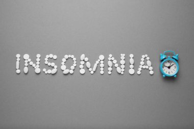 Sleeping pills and an alarm clock, insomnia concept. Drugs for treating sleep problems.