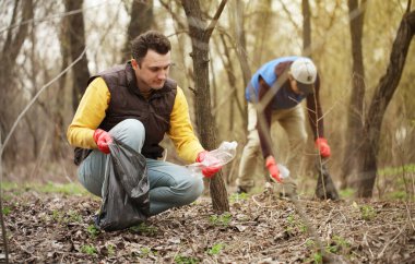 Bağış gönüllüleri ormandaki çöpleri topluyor, doğayla ilgileniyor. Parkta bahar temizliği, çöpler ve çöpler..