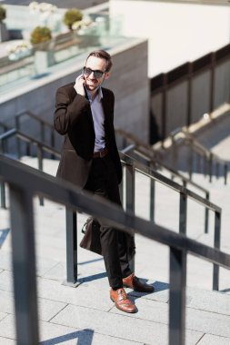 Business man raised his glasses to watch good news on phone, pleasant surprise.