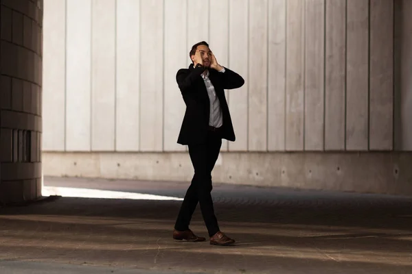 stock image Young businessman in despair holds his hands behind his head in gateway.