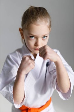 Karate duruşu savunması, beyaz arka planda ciddi bir dövüşçü kızın portresi..