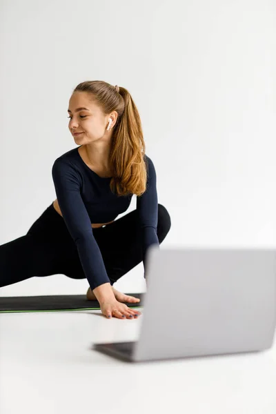 Młoda Kobieta Trening Online Laptopem Białym Studio Joga Rozciąganie — Zdjęcie stockowe