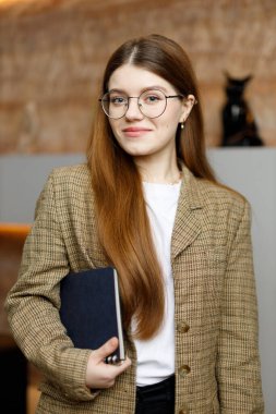 Elinde not defteri olan genç bir kadın stajyerin portresi. Okulda bir öğrenci..
