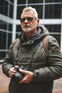 Mature man with camera, hobby. Portrait of a reporter photographer.