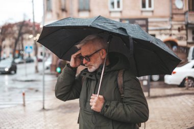 Migraine and headache when the weather changes. Unpleasant symptoms in a mature man in the rain.