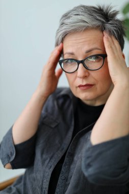 Gözlüklü yaşlı kadın ellerini başının arkasında tutuyor, yakın plan portre. Sorunlar ve deneyimler.