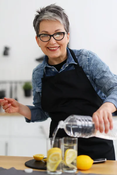 Портрет Позитивної Жінки Кухні Вливає Воду Окуляри Лимоном — стокове фото