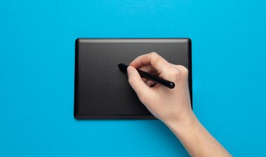 Graphic tablet for drawing and designer hand on blue background. Creative art, sketch.