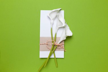 Tebrikler ve bayram davetiyesi. Calla çiçekleri ve yeşil arka planda bir not..