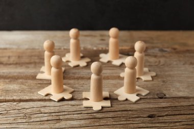 Wooden figures on puzzles. People analytics and optimization, team building. Group connection in business.