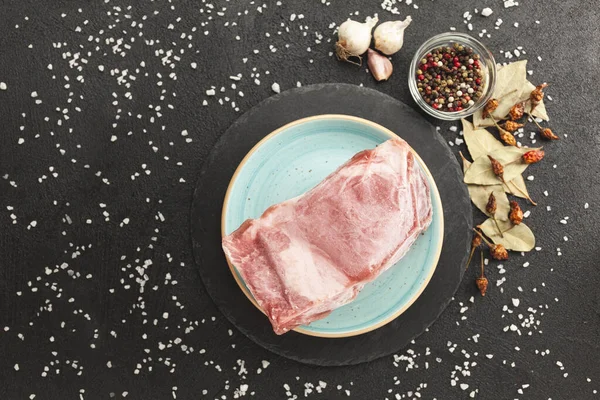 stock image Frozen piece of raw meat on plate on black table. Rime on product, thawing.