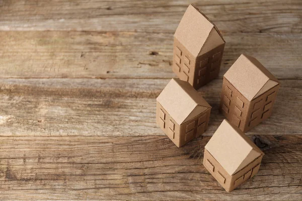 stock image Cardboard toy houses on wooden background. Sale or rental of housing. Neighbors in house. Comfortable life in suburbs.