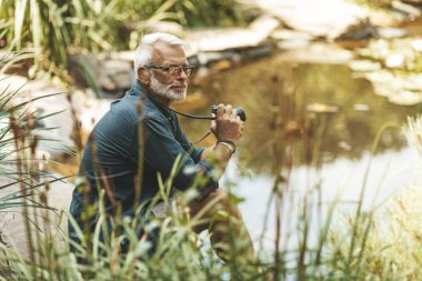 Yaşlı bir adam doğayla baş başa dinleniyor. Emekli turist gölün kenarında oturuyor..