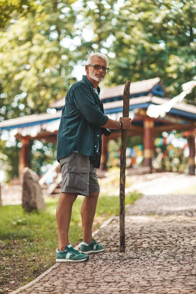 stock image An old man with a stick and a backache is walking in the park. Hike in the 60s.