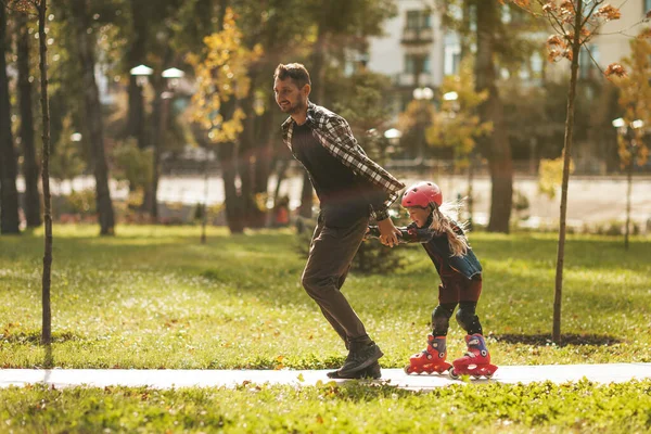 Baba ve kızı parkta eğleniyorlar. Baba paten sürerken çocuğu çeker..