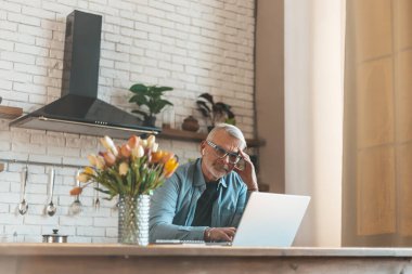 Ne pişireceksin? Evde dizüstü bilgisayarla yemek tarifi arayan olgun bir adam. Restorandan sipariş veriyorum..