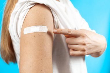 Aşıdan sonra. Yakın plan, mavi arka plan enjeksiyonundan sonra alçıyla..