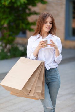 Priz satışı. Alış veriş yapan ve dışarıda kahve içen güzel bir kız. Bir butikte alışveriş..