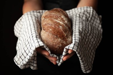 Siyah arka planda havlunun üstünde çavdar ekmeği. Fırından taze pişmiş yiyecekler..