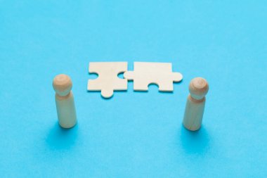 Wooden figures with pazzles on blue background. Agreement between business mans, cooperation and deal concept. Successful contract. 