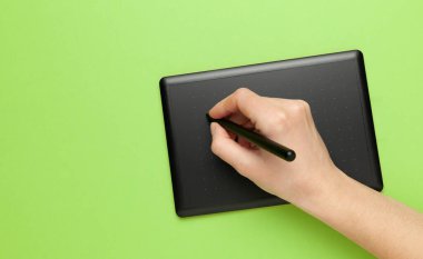 Yeşil zemin üzerinde çizim ve tasarımcı eli için grafiksel tablet. Yaratıcı sanat, taslak.