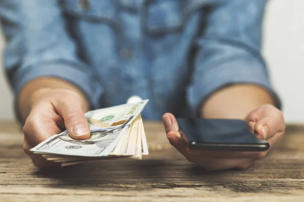 stock image Woman holds dollars and phone in her hands. Online money transfer.