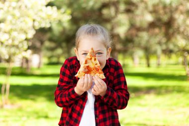 Parktaki küçük kız elinde bir dilim pizzayla. Yemek servisi, yaz pikniği..