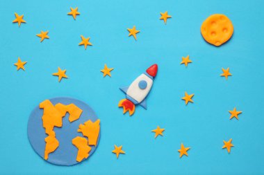 Açık alanda yaratıcı el yapımı plastik roket, astronot rüyaları. Yıldızlar, dünya ve ay gezegeni. Çizgi film sanatı.