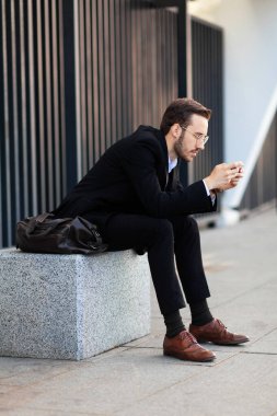 Modern young man playing on phone, browsing mobile news. Gadget Dependence.