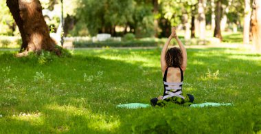 Parktaki güzel Avrupalı kadın fiziksel egzersizler, esnemeler, yoga yapıyor. Esnekliği geliştirmek için duruş.