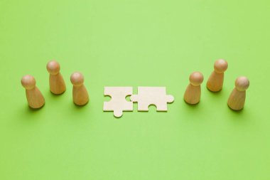 Yeşil arka planda pazzleri olan tahta figürler. İş adamları arasındaki anlaşma, işbirliği ve anlaşma konsepti. Başarılı bir sözleşme.. 